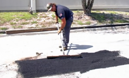 A worker repairing damaged asphalt